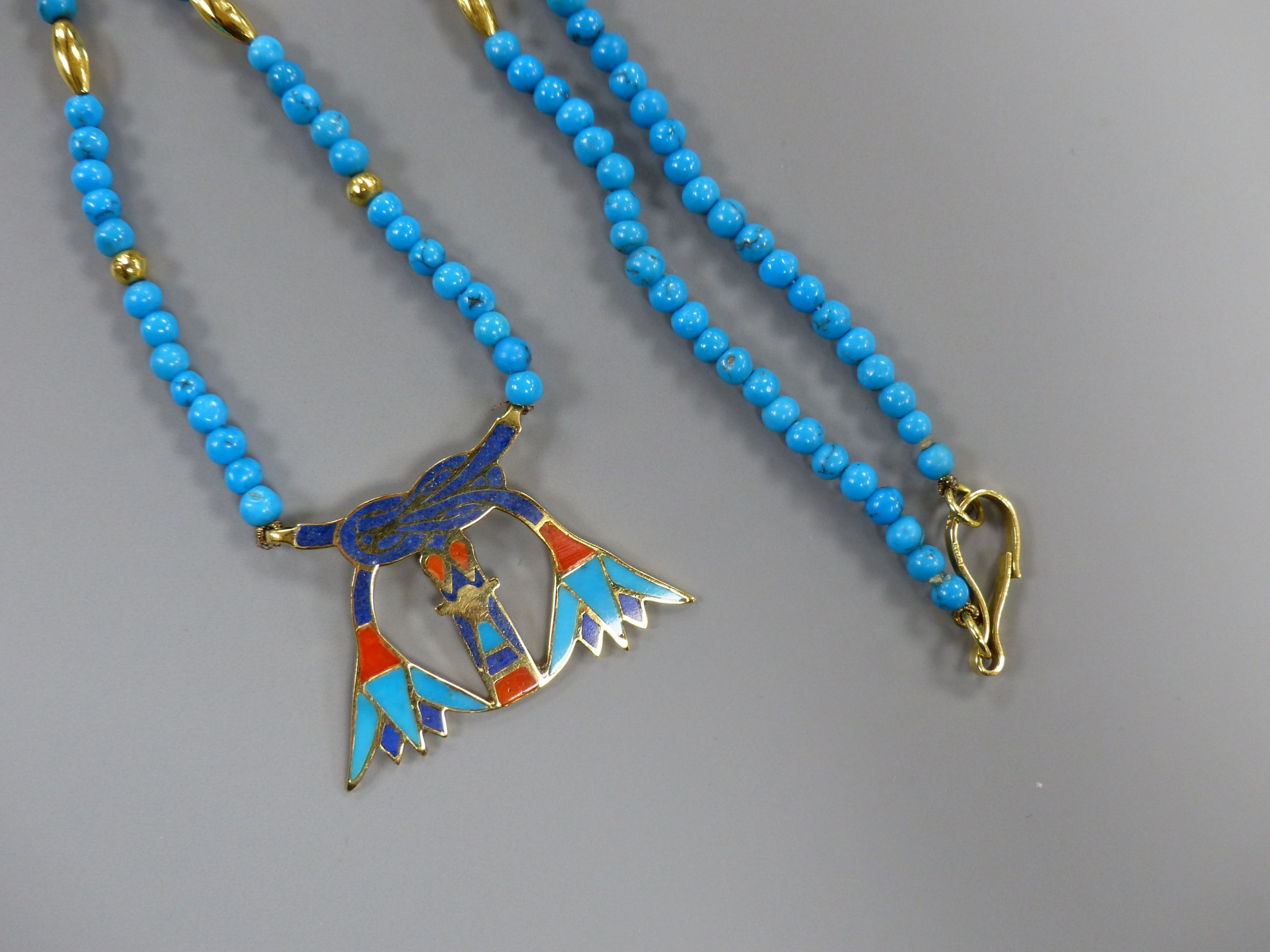An Egyptian enamelled yellow metal pendant on turquoise and yellow metal bead necklace, the clasp marked 750, 54cm,